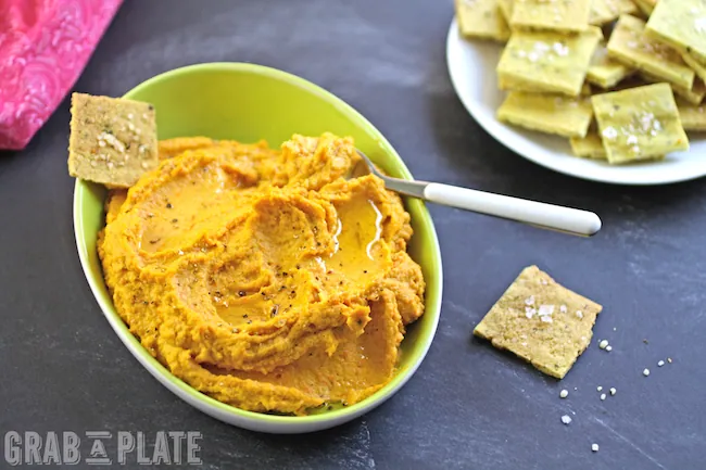 Dig into a bowl of Carrot Hummus with Curried Hemp Seed Crackers