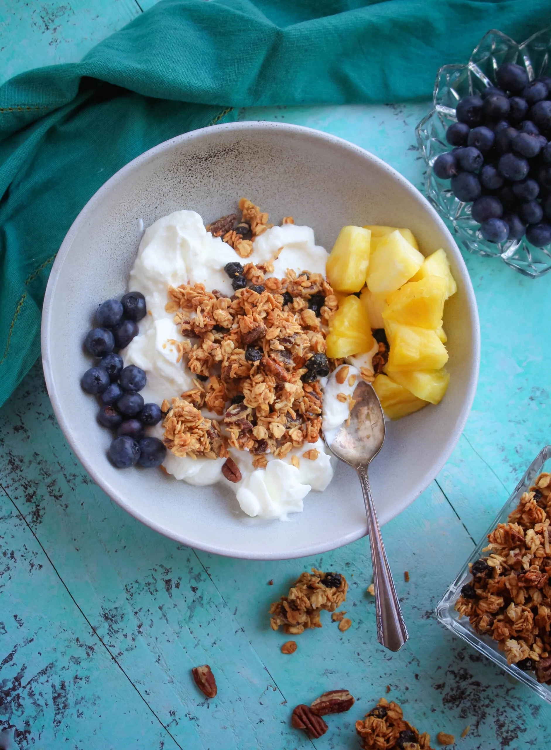 Looking down on a bowl of plain yogurt with granola and fruit.