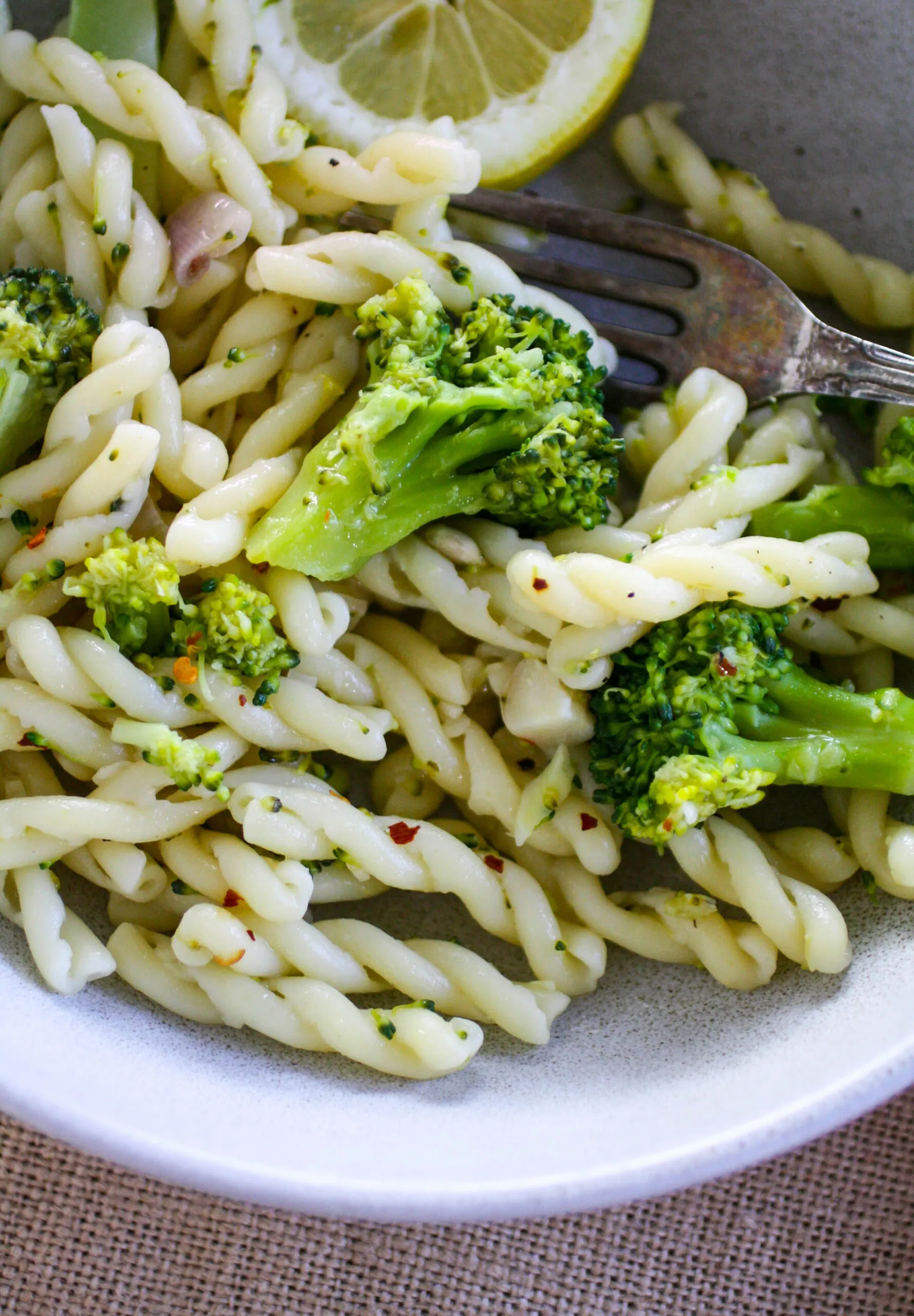 A bowl of spiral pasta with broccoli florets tossed with it.