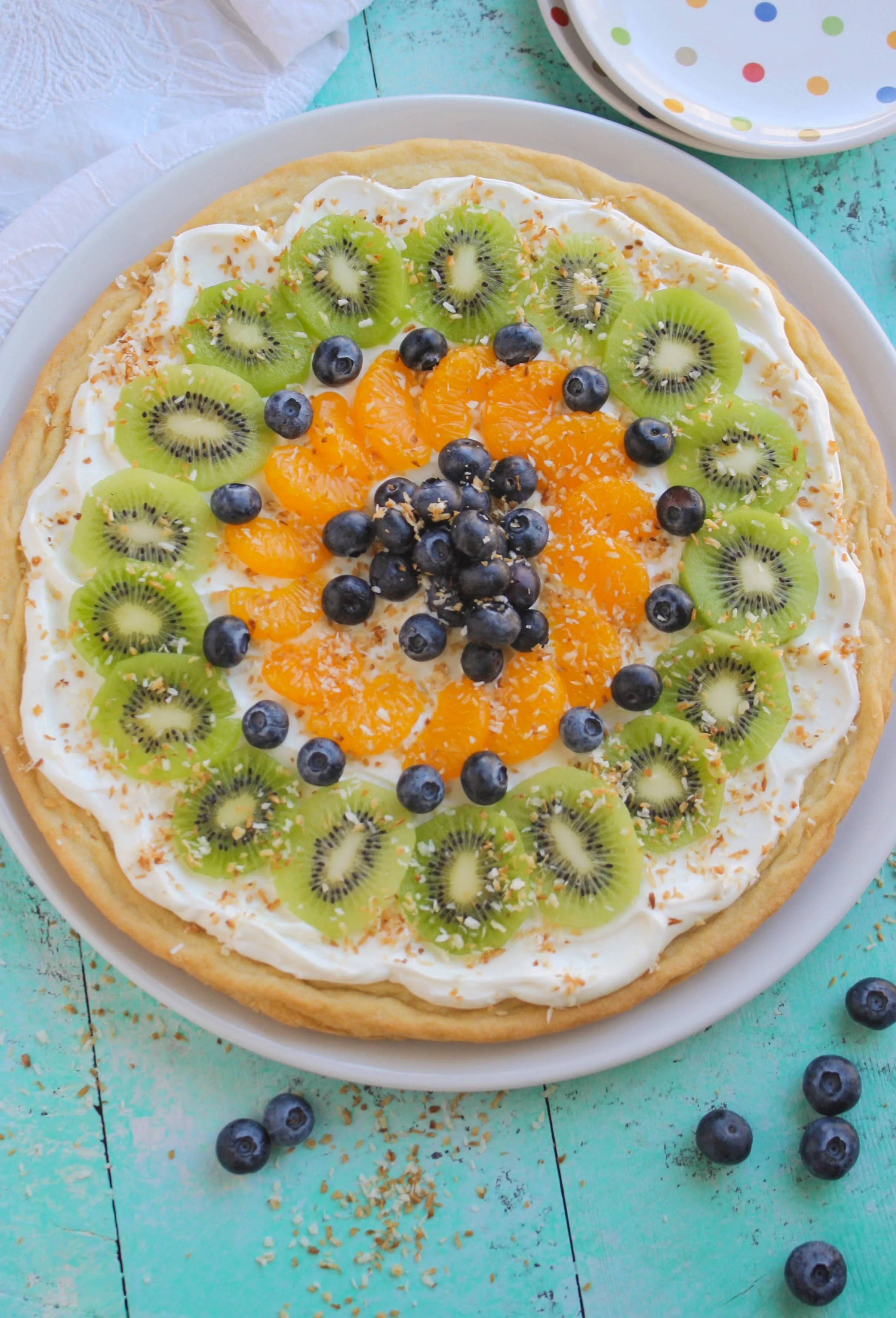Sugar Cookie Fruit Pizza is a pretty and fun dessert! A sugar cookie crust gets topped with a great spread and all sorts of fruit!
