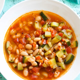 A white bowl full of White Bean and Zucchini Soup.