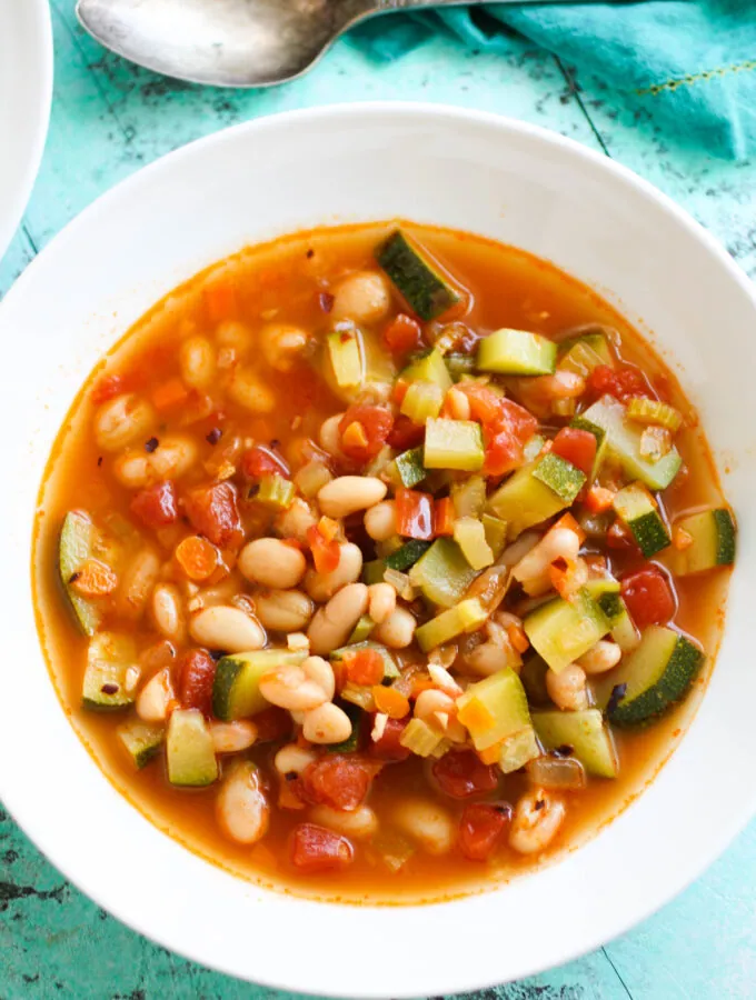 A white bowl full of White Bean and Zucchini Soup.